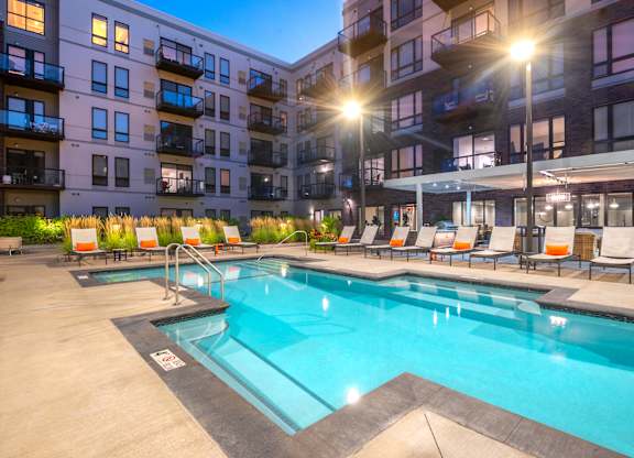 a swimming pool in front of an apartment building at night