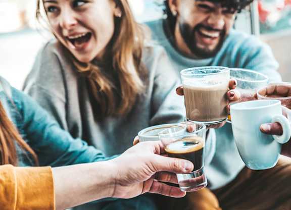 a group of people holding up cups of coffee