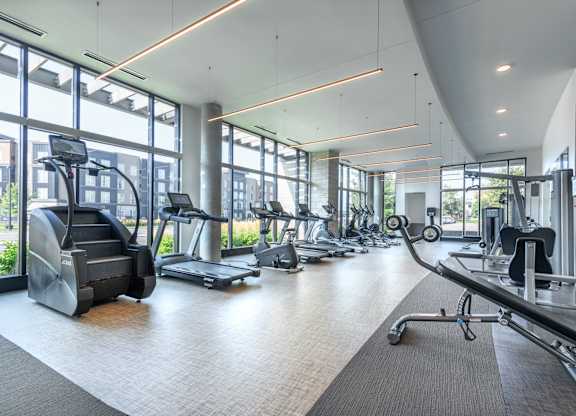 a gym with cardio equipment and windows in a building