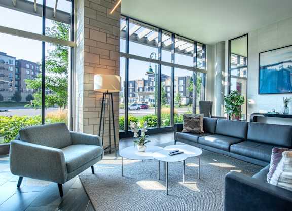 a living room with couches and chairs and large windows