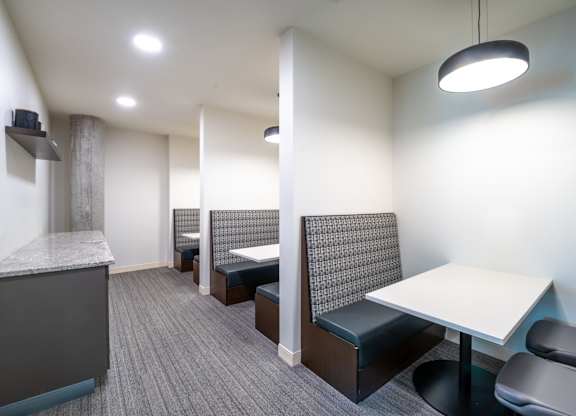 a communal area with tables and chairs and a kitchen