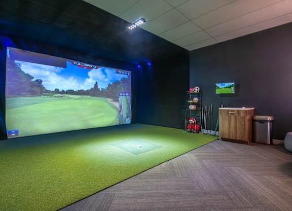 a room with a projector screen and a golf game on the wall