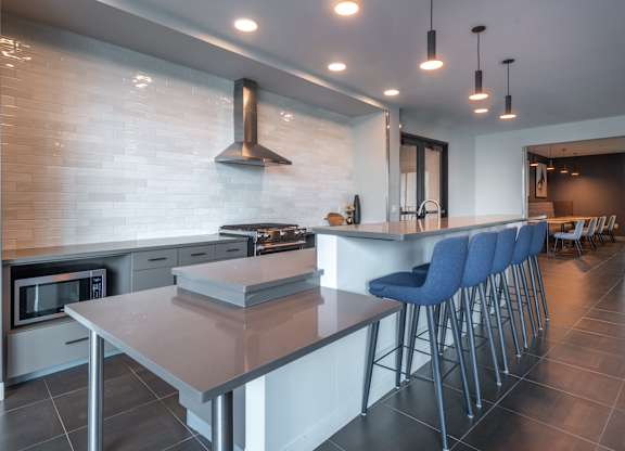 a kitchen with a long island with bar stools and a stove and a microwave