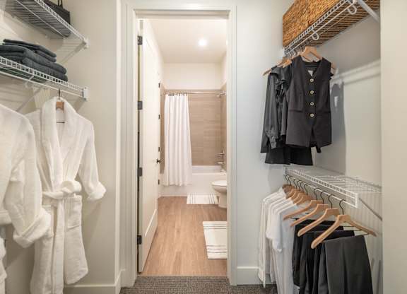 a walk in closet filled with clothes and a door to a bathroom