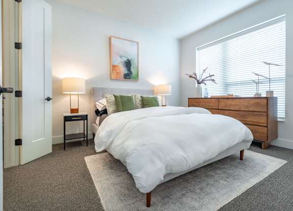 a bedroom with a bed and a dresser and a window