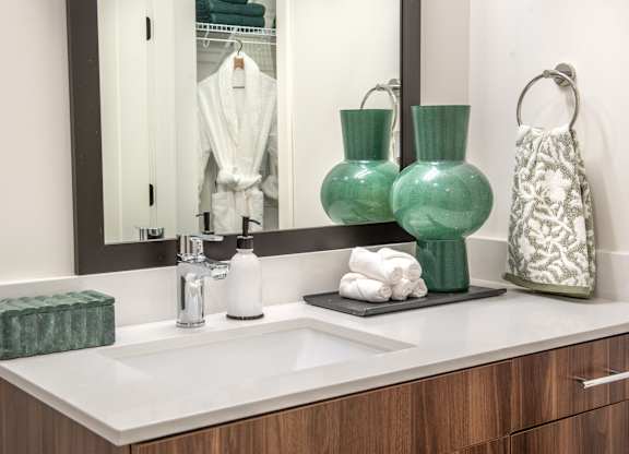 a bathroom sink with green vases and a mirror