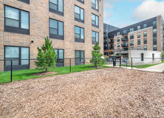 a dog park in front of a brick building with a chain link fence