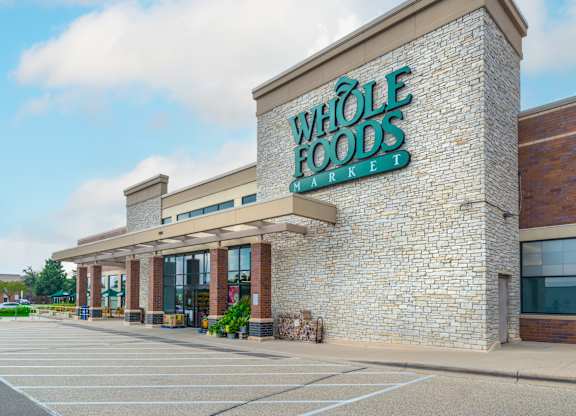 the exterior of a foods store with a brick facade and a green sign
