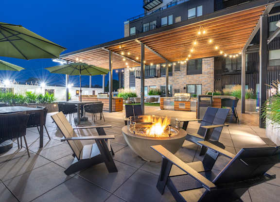 a patio with tables and chairs and a fire pit