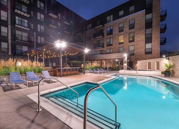 a swimming pool at night in front of an apartment building