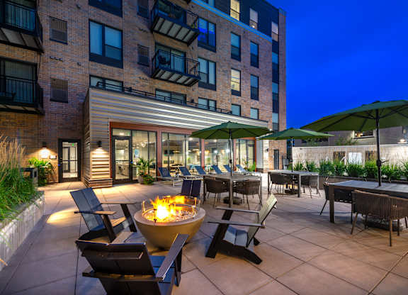 an outdoor patio with chairs and a fire pit at night
