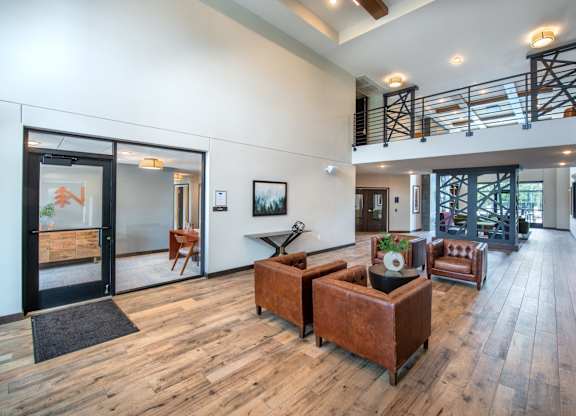 a living room with couches and chairs and a staircase in the distance