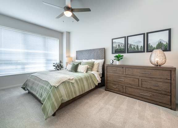 a bedroom with a large window and a ceiling fan
