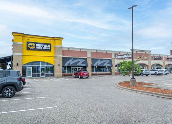the exterior of a shopping center with cars parked in a parking lot