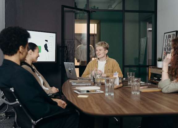 A group of people are sitting around a table in a meeting room.
