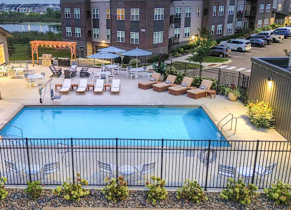 an aerial view of a swimming pool with lounge chairs at night