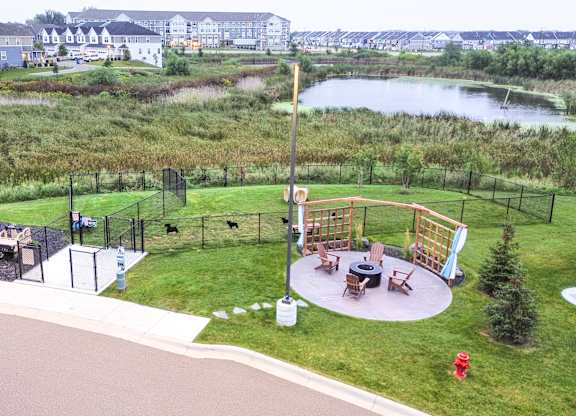 a playground with a fire pit and a pond in a park