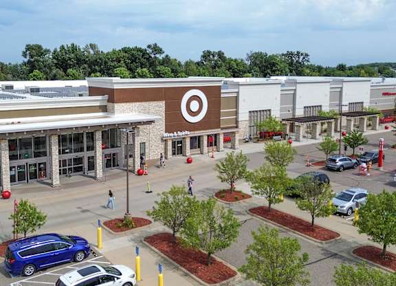 an aerial view of the exterior of a shopping center with parking lot and cars
