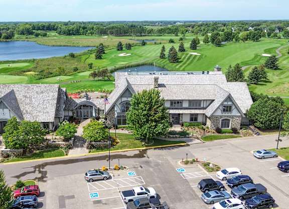 an aerial view of a mansion with a golf course and a lake