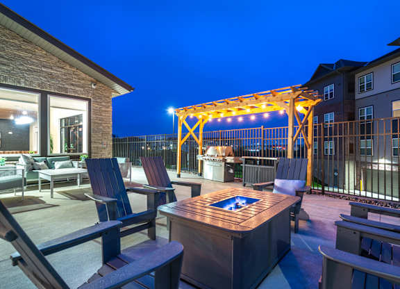 a patio with a fire pit and chairs at night