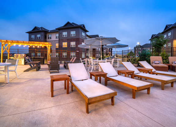 an outdoor patio with lounge chairs and umbrellas at dusk