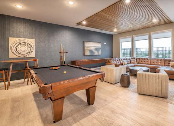 a community room with a pool table and couches and chairs