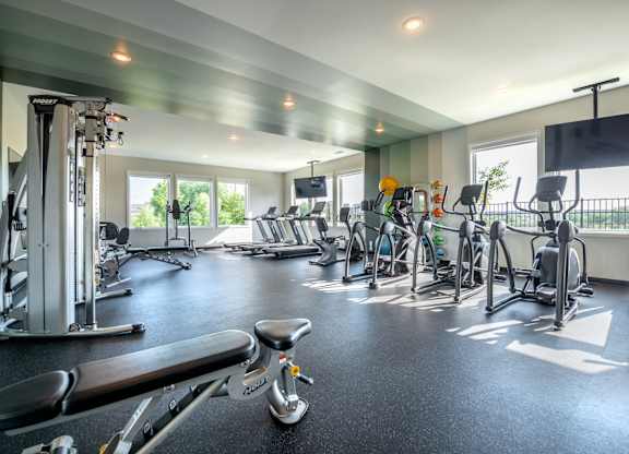 a gym with weights and cardio equipment and windows