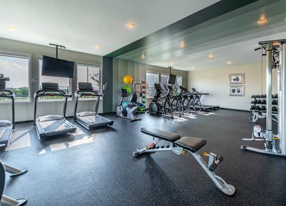 a gym with treadmills and other exercise equipment and windows