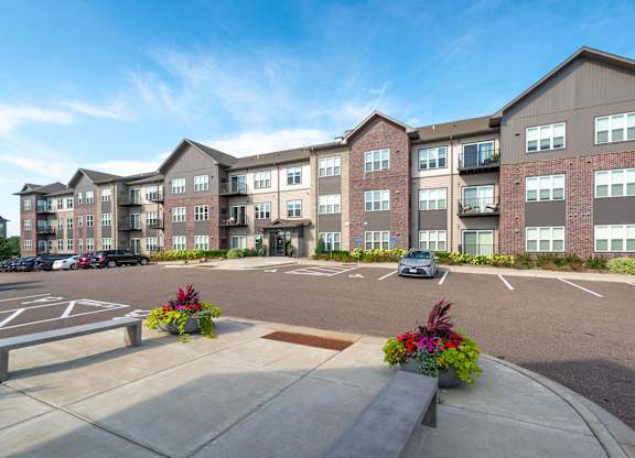 an exterior view of an apartment building in a parking lot