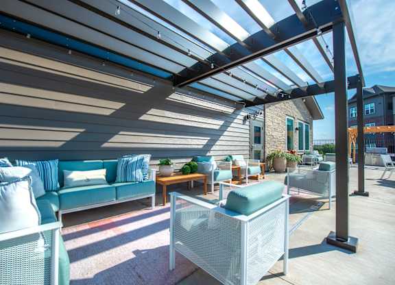 a patio with blue couches and chairs and a pergola