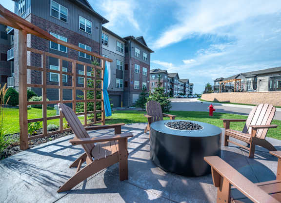 an outdoor patio with a fire pit and wooden chairs