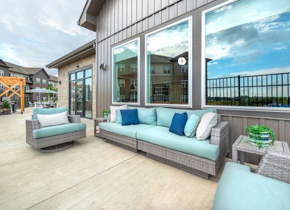a covered porch with wicker furniture and large windows
