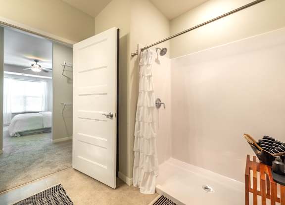 a bathroom with a shower and a closet and a bed