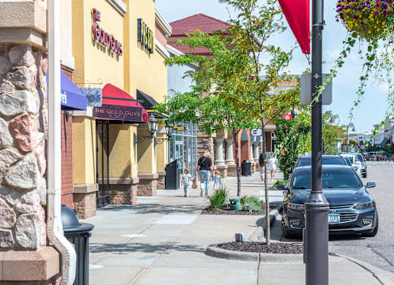 a city street with cars parked on the sidewalk and people walking