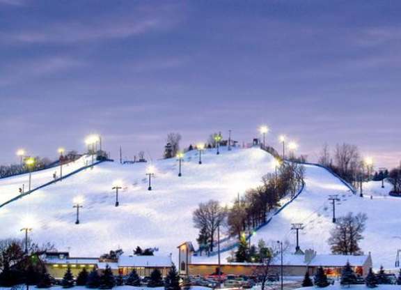 A ski slope is lit up at night.