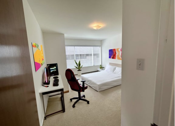 a bedroom with a bed and a desk in a room