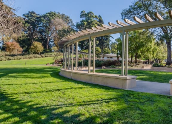 a pergola in a park with a playground in the background