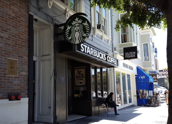 a person sitting in a chair in front of a starbucks coffee shop on a city street