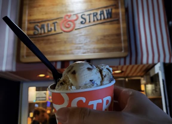 a cup of ice cream in front of a salt and straw sign