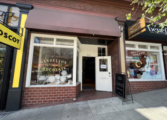 a brick building with a white door and a window with a sign that reads dandelion