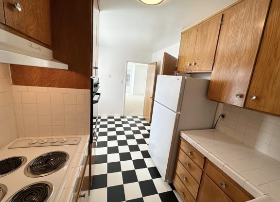 a small kitchen with white appliances and a black and white checkered floor