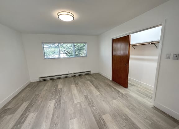 a bedroom with hardwood floors and white walls