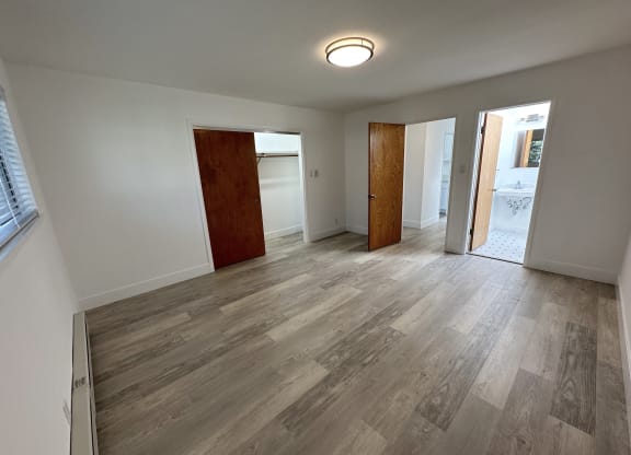 a bedroom with hardwood floors and white walls