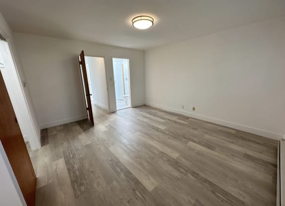 a bedroom with hardwood floors and white walls