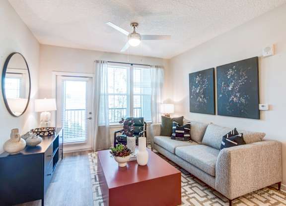 A living room with ceiling fan and private balcony/patio access at Tapestry Nona in Orlando, FL