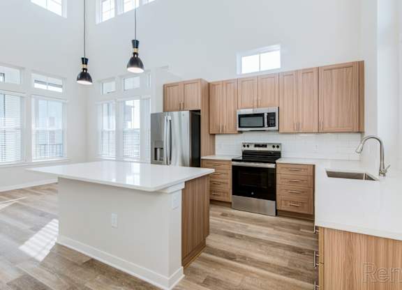 Island kitchen with natural light, quartz countertops, and undermount sink at Tapestry Nona Apartments in Orlando, FL