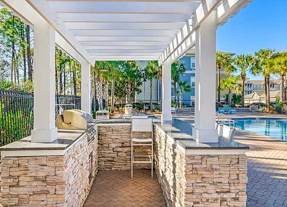 A patio with a stone wall and a grill.