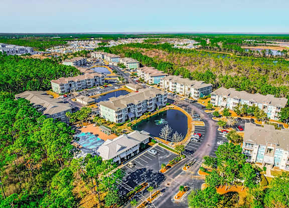 A bird's eye view of a residential complex with a swimming pool and a roundabout.