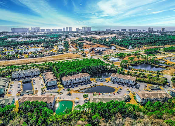 A bird's eye view of a residential complex surrounded by trees and a body of water.