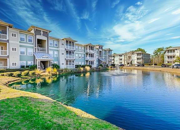 A row of apartment buildings are next to a body of water.